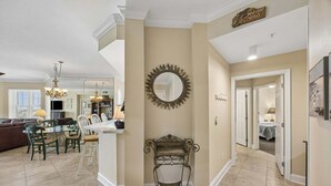 A spacious living area with a dining table, chairs, and a decorative mirror. - Oceanfront, Bottom Floor condo with pool, balcony, washer/dryer (Fernandina Beach)