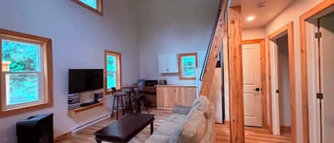 A spacious living area with a sofa, television, and wooden flooring.