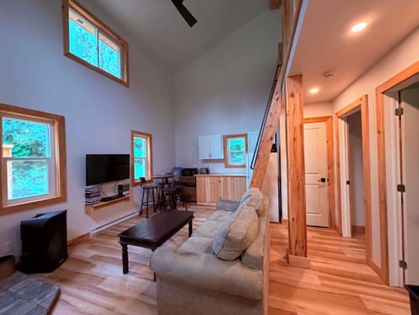 A spacious living area with a sofa, television, and wooden flooring.