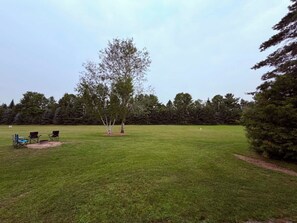 A grassy outdoor area with a few trees and a picnic setup.