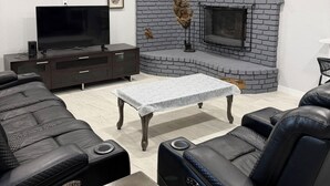 A modern living room with a flat-screen TV, a fireplace, and a sofa. - Spacious 4-bedroom house in tranquil Lakeside with AC (Lakeside)