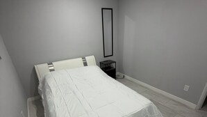 A bedroom with a bed, a nightstand, a mirror, and a wall-mounted vent. - Spacious 4-bedroom house in tranquil Lakeside with AC (Lakeside)