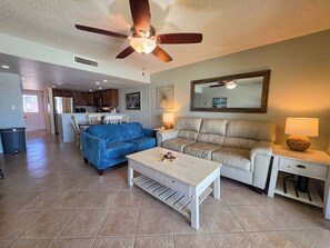 A living room with a blue sofa, a white coffee table, a beige sofa, and a ceiling fan. - Waterfront views • Walk to Beach • Riverfront pool • Dog-friendly (St. Augustine)