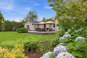 A residential property with a well-maintained lawn, a patio with outdoor furniture, and a variety of plants and flowers. - Spacious McMinnville Retreat | 5 Bedrooms | Pet Friendly (Mcminnville)