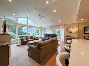 A spacious living room with a large window, a ceiling fan, and a dining area with a table and chairs. - Spacious McMinnville Retreat | 5 Bedrooms | Pet Friendly (Mcminnville)