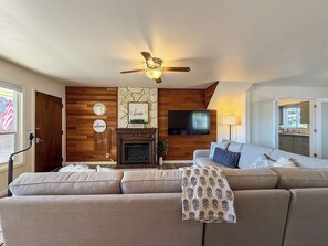 Ein Wohnzimmer mit Kamin, Fernseher und einer Couch.