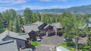 A lodge with multiple buildings, a parking area, and a mountainous backdrop. - Brand-New Feel 3BR + Loft | Private Hot Tub, Ski Views & Garage | Steps to Free Bus (Steamboat Springs)
