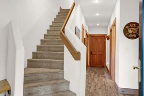 A staircase with a wooden handrail leading to a wooden door at the end. - Brand-New Feel 3BR + Loft | Private Hot Tub, Ski Views & Garage | Steps to Free Bus (Steamboat Springs)