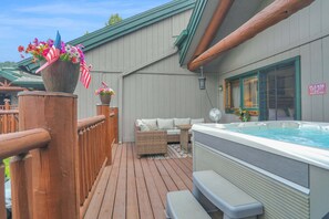 A wooden deck with a hot tub, outdoor seating, and a sign indicating a dry-off requirement before entering. - Brand-New Feel 3BR + Loft | Private Hot Tub, Ski Views & Garage | Steps to Free Bus (Steamboat Springs)
