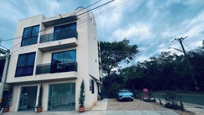 Un edificio de varios pisos con fachada plana, amplias ventanas y una entrada visible con puerta de vidrio.