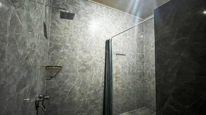 Un baño moderno con cabina de ducha de vidrio, ducha de mano y grifo empotrado.