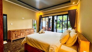Habitación de hotel con una cama grande, un aparador de madera y vistas al exterior a través de un ventanal.