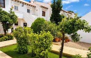 A courtyard with a white building, a staircase, and various potted plants. - Beautiful apartment in Torrevieja with outdoor swimming pool (Torrevieja)