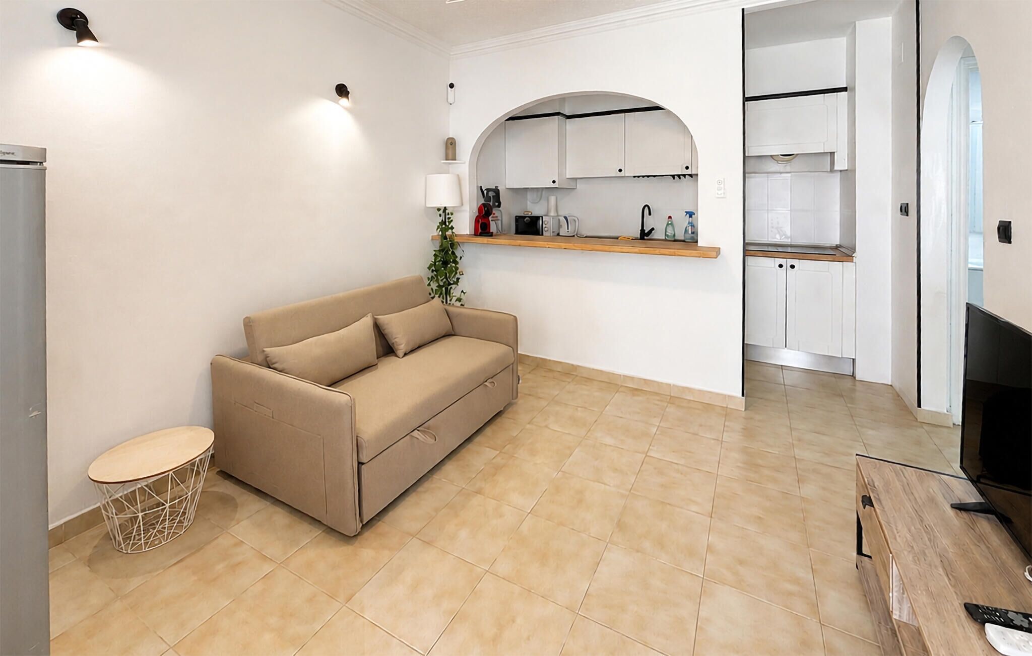 Una sala de estar con un sofá, una mesita redonda y un mueble para televisión.