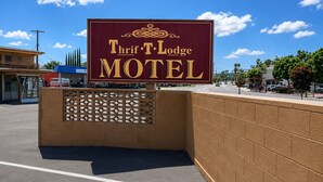 A sign for Thrif T-Lodge Motel with a clear view of the entrance and parking area.
