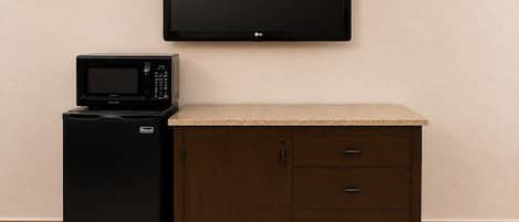 Una kitchenette equipada con microondas, refrigerador y un televisor de pantalla plana montado en la pared.