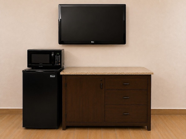 Una kitchenette equipada con microondas, refrigerador y un televisor de pantalla plana montado en la pared.