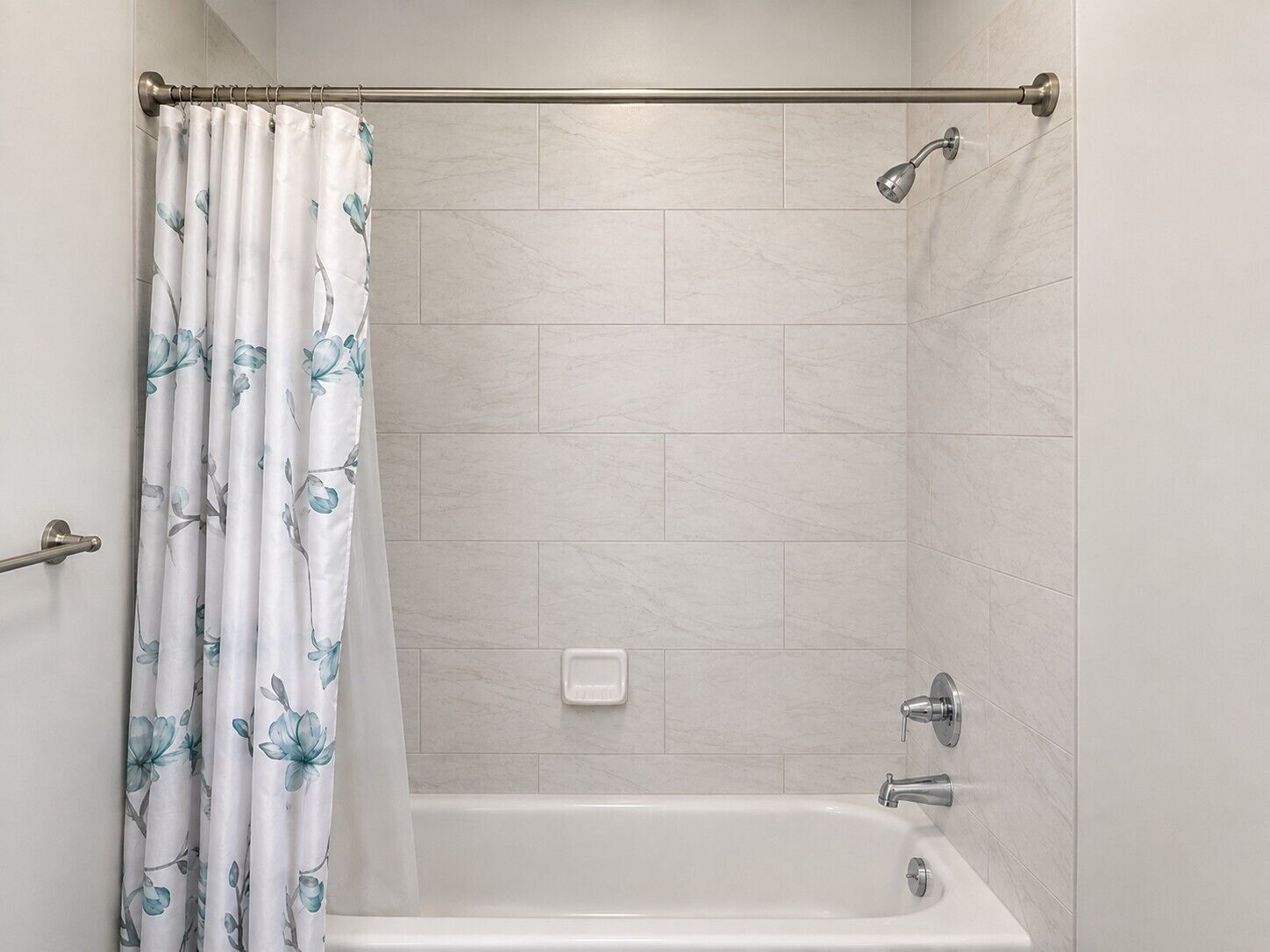 A bathroom with a shower curtain, a bathtub, and a showerhead.