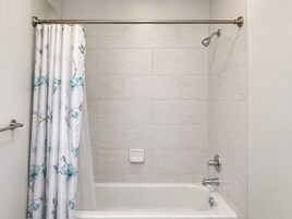 Un baño con cortina de ducha, bañera y cabezal de ducha.