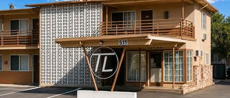 A two-story building with a balcony, a sign with 'TL' on it, and a number '24' on the side.