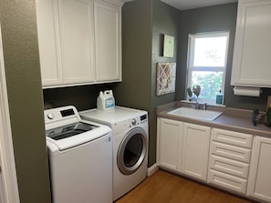 A laundry room with two washing machines, a sink, and cabinets.