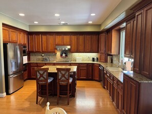A kitchen with wooden cabinets, a stainless steel refrigerator, a granite countertop, and a built-in oven. - Custom Ranch style home with a Citrus grove and swimming pool on 12 acres. (Sloughhouse)