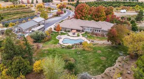 A residential property with a swimming pool, a covered patio, and a large lawn.
