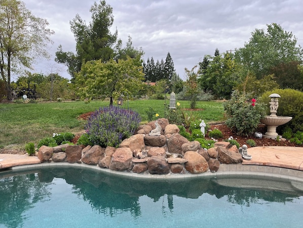 A swimming pool with a rock feature and a statue of a child.