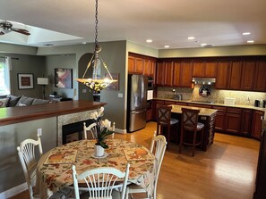 A modern kitchen with wooden cabinets, a stainless steel refrigerator, and a dining area with a floral tablecloth.
