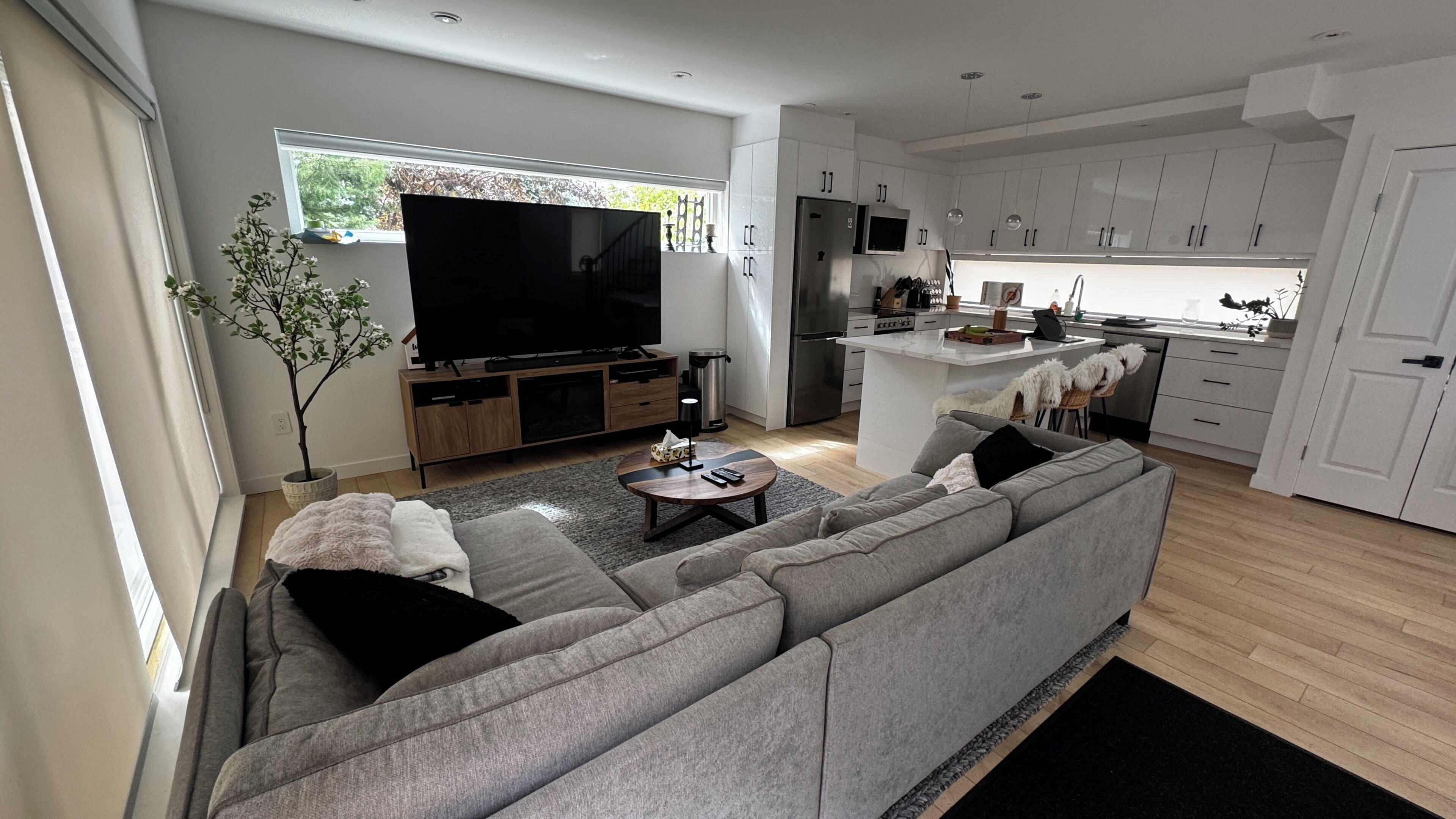 Ein modernes Wohnzimmer mit einem grauen Sofa, einem Flachbildfernseher und einem kleinen Couchtisch.