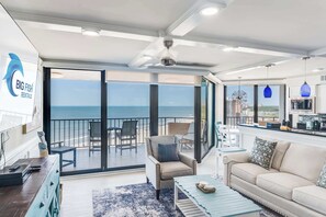 A spacious living area with a balcony overlooking the sea, a kitchenette, and a seating area with a sofa and armchairs. - Oceanfront Condo, Amazing View, Large 2 Bedroom (Myrtle Beach)