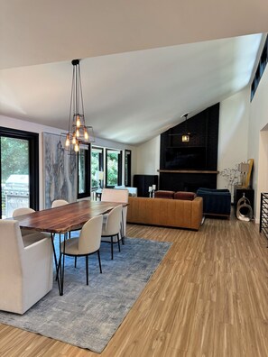 A modern living room with a wooden dining table, white sofas, and a large window. - Modern Luxe Estate~Pool·HotTub·2AcresPrivateResort (Issaquah)