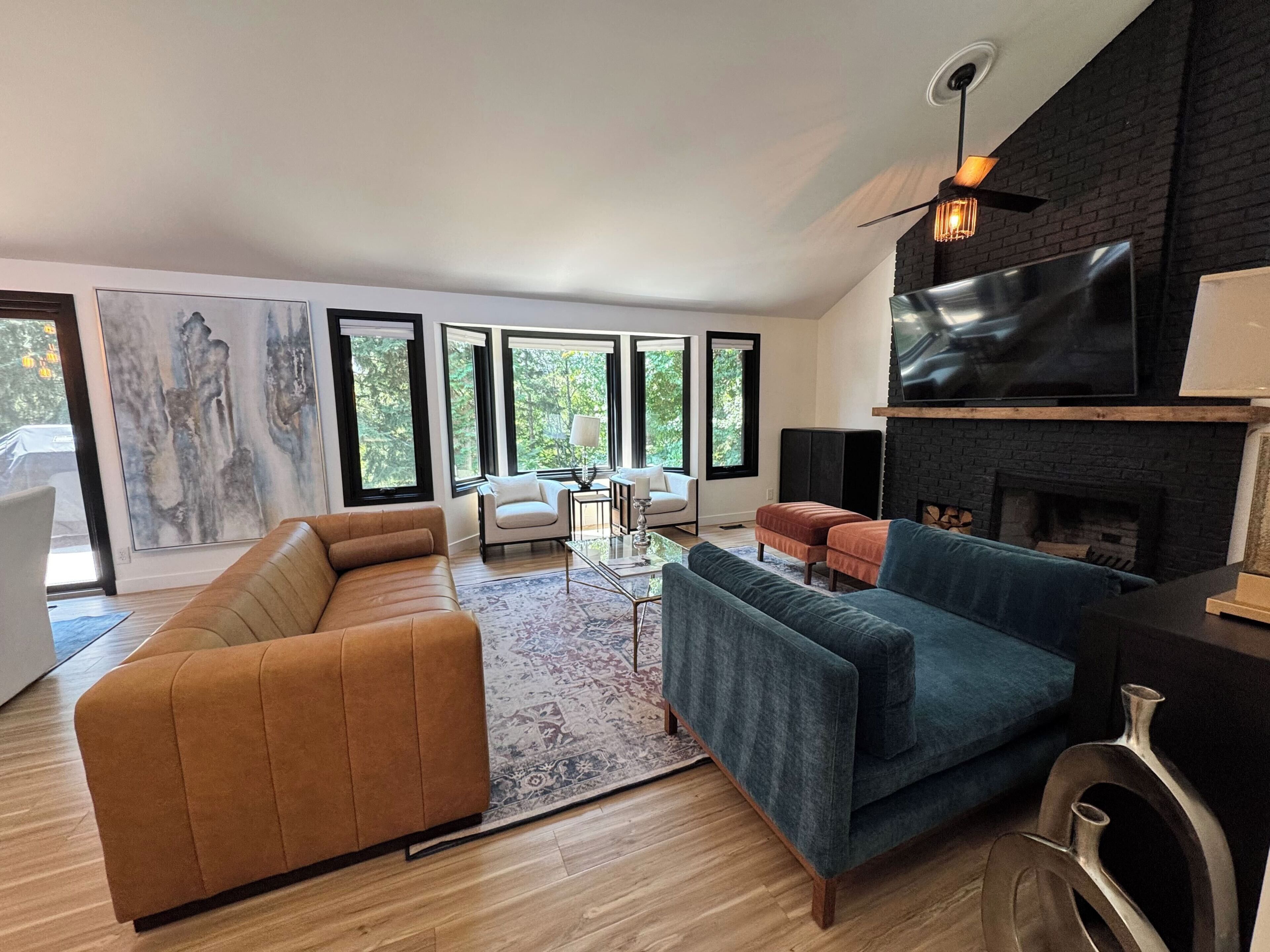 Een moderne woonkamer met een open haard, grote ramen en een flatscreen televisie.