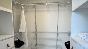 Ein begehbarer Kleiderschrank mit Metallregalen, Holzboden und weißen Wänden.