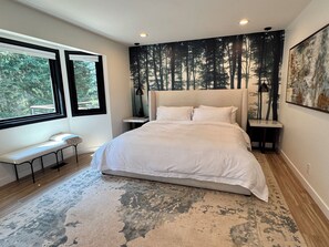 A bedroom with a large bed, a bench, a window, and a forest-themed wall mural. - Modern Luxe Estate~Pool·HotTub·2AcresPrivateResort (Issaquah)