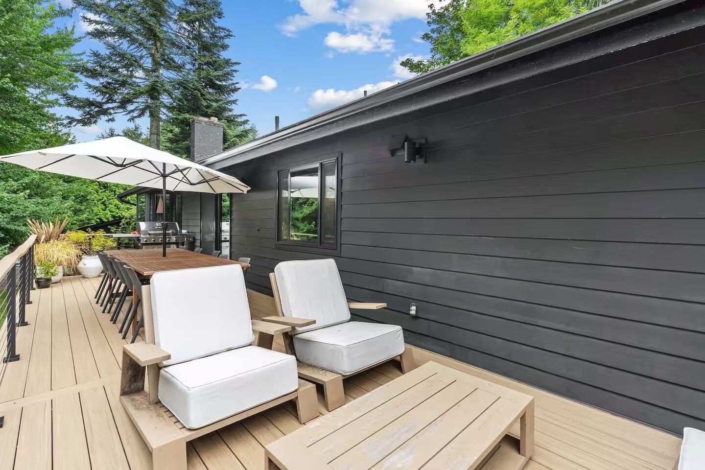 Een terras met een tafel, stoelen, een barbecue en een parasol.