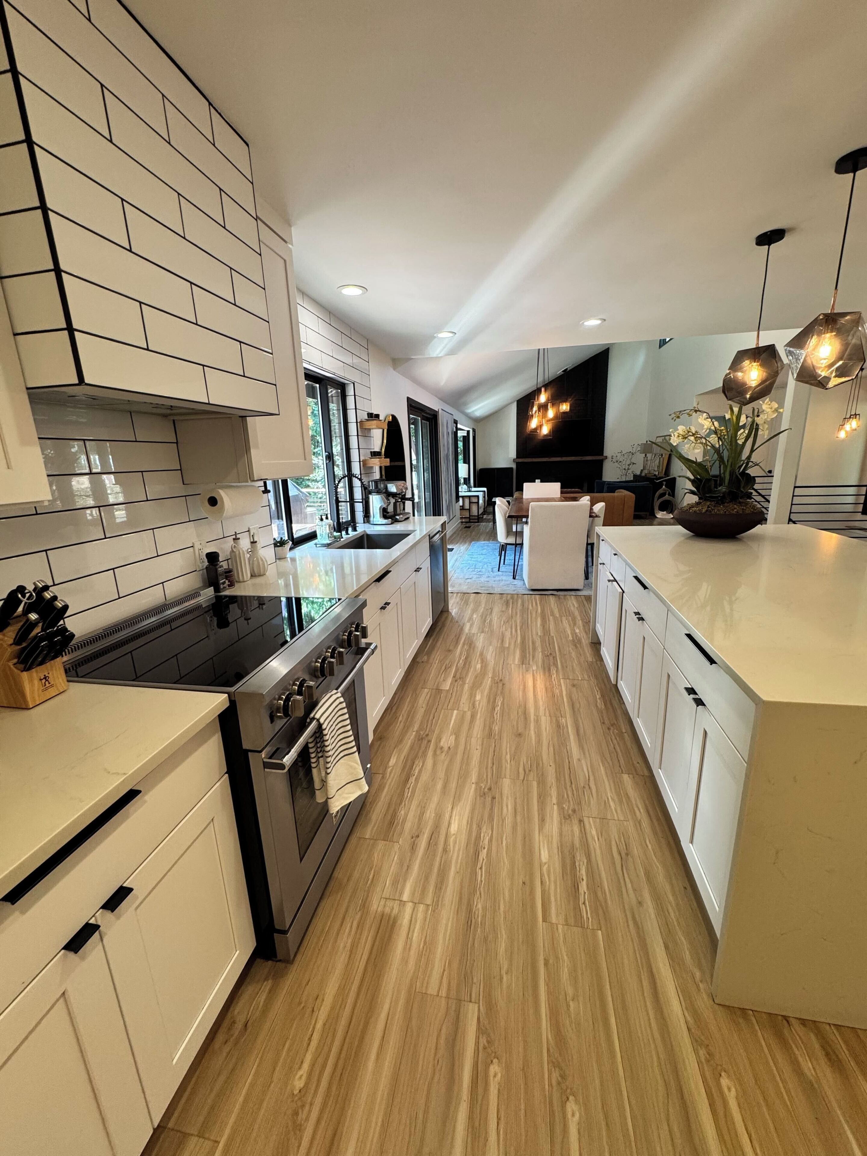 Een moderne keuken met een centraal eiland, roestvrijstalen apparatuur en een houten vloer.