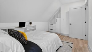 A modern bedroom with a bed, a desk, and a wardrobe.