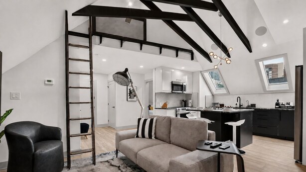 A modern living space with a loft bedroom, a kitchen, and a dining area.
