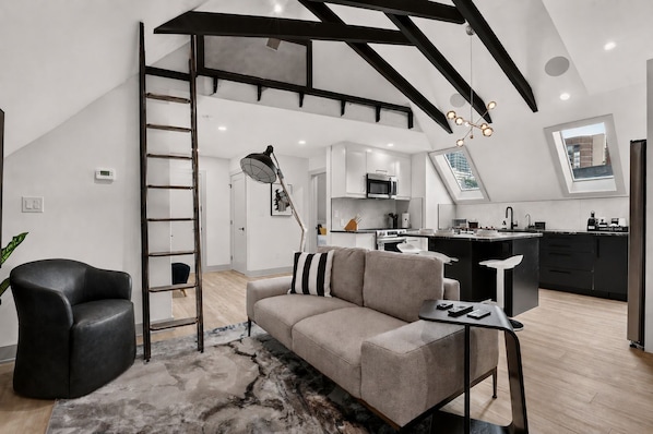 A modern living space with a loft bedroom, a kitchen, and a dining area.