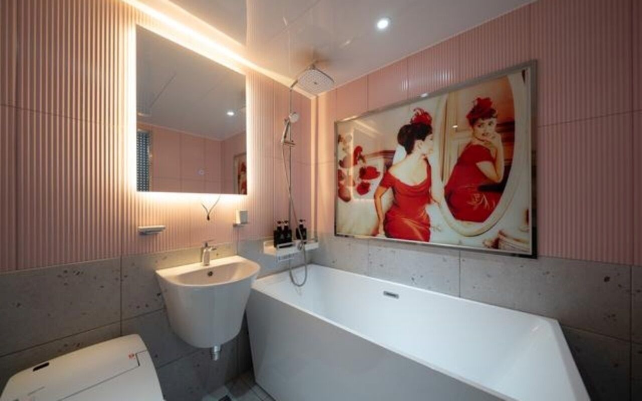 A modern bathroom with a large mirror, a bathtub, and a sink.