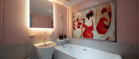 A modern bathroom with a large mirror, a bathtub, and a sink.