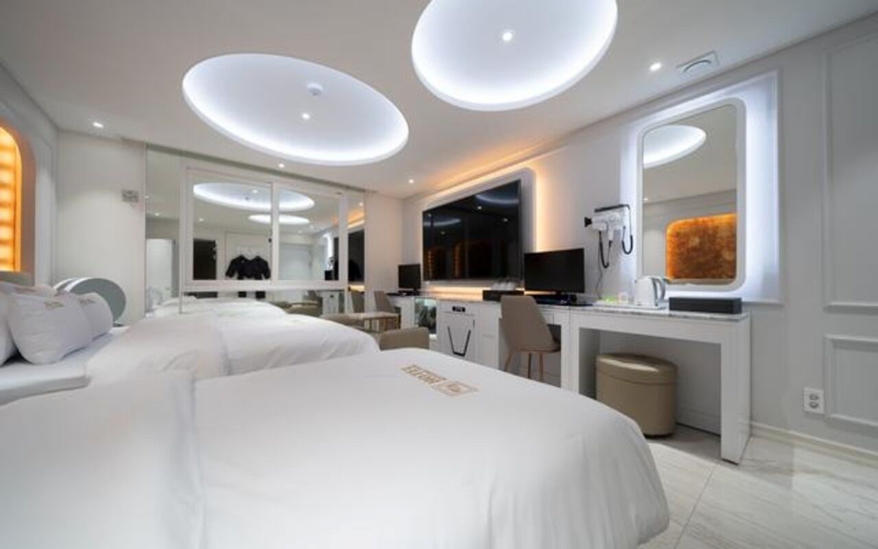 A modern hotel room with a large bed, a desk, and a mirror.