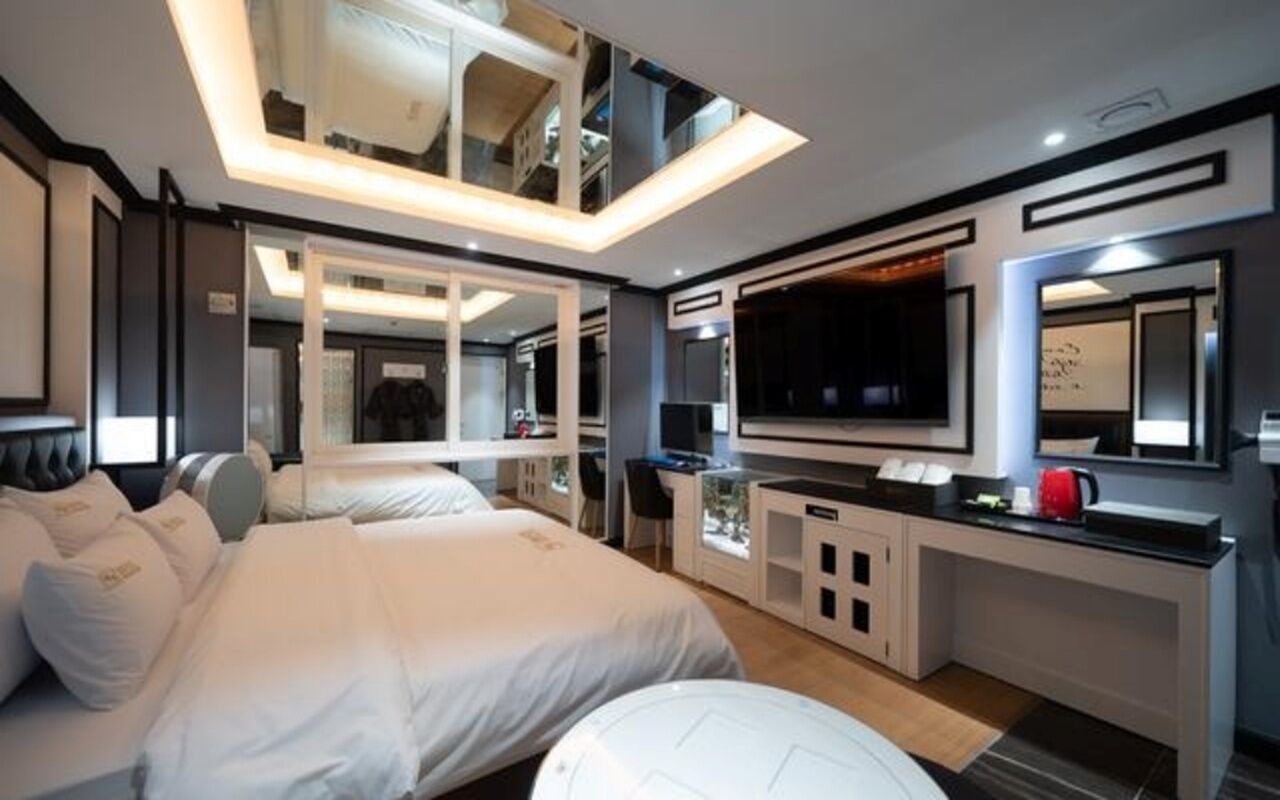 Un dormitorio moderno con una cama grande, una televisión y un espejo.