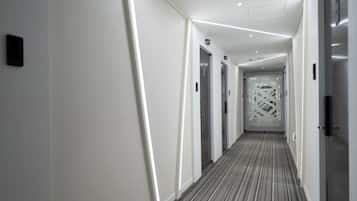 Corredor moderno de hotel com caminho reto, portas e carpete estampado.