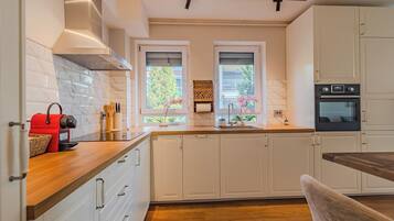 A modern kitchen with white cabinets, a wooden countertop, a red toaster, and a window with a view of greenery.