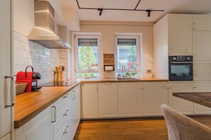 Eine moderne Küche mit weißen Schränken, einer Holzarbeitsplatte, einem roten Toaster und einem Fenster mit Blick auf Grünflächen.