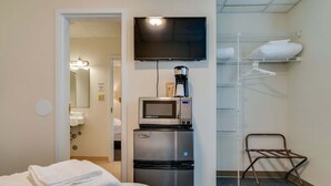 A hotel room with a bed, a TV, a coffee maker, a microwave, a shelf with towels, and a chair. - Converted Suite in the Historic Scarritt Bennett!! (Nashville)