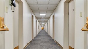 Pitkä, kapea hotellikäytävä, jossa on matotetut lattiat ja valkoiset seinät.
