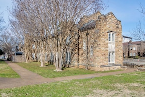 Un bâtiment en pierre avec une façade en briques, un trottoir et des arbres sans feuilles.